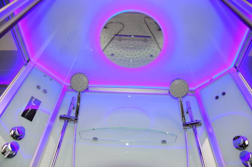 Modern shower cabin with multiple shower heads and LED lighting.