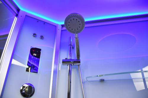 Shower head in a shower enclosure with purple lighting