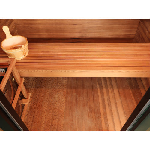 A wooden sauna interior with a raised bench, wooden floor, and a light wood ladle resting on the bench.