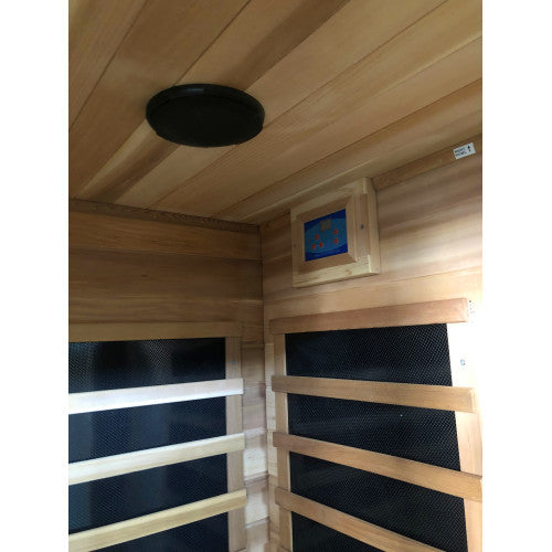 Wooden sauna with black mesh panels and a ceiling light fixture.