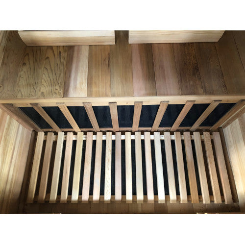 Wooden crib with slatted base and top rail on a wooden floor.