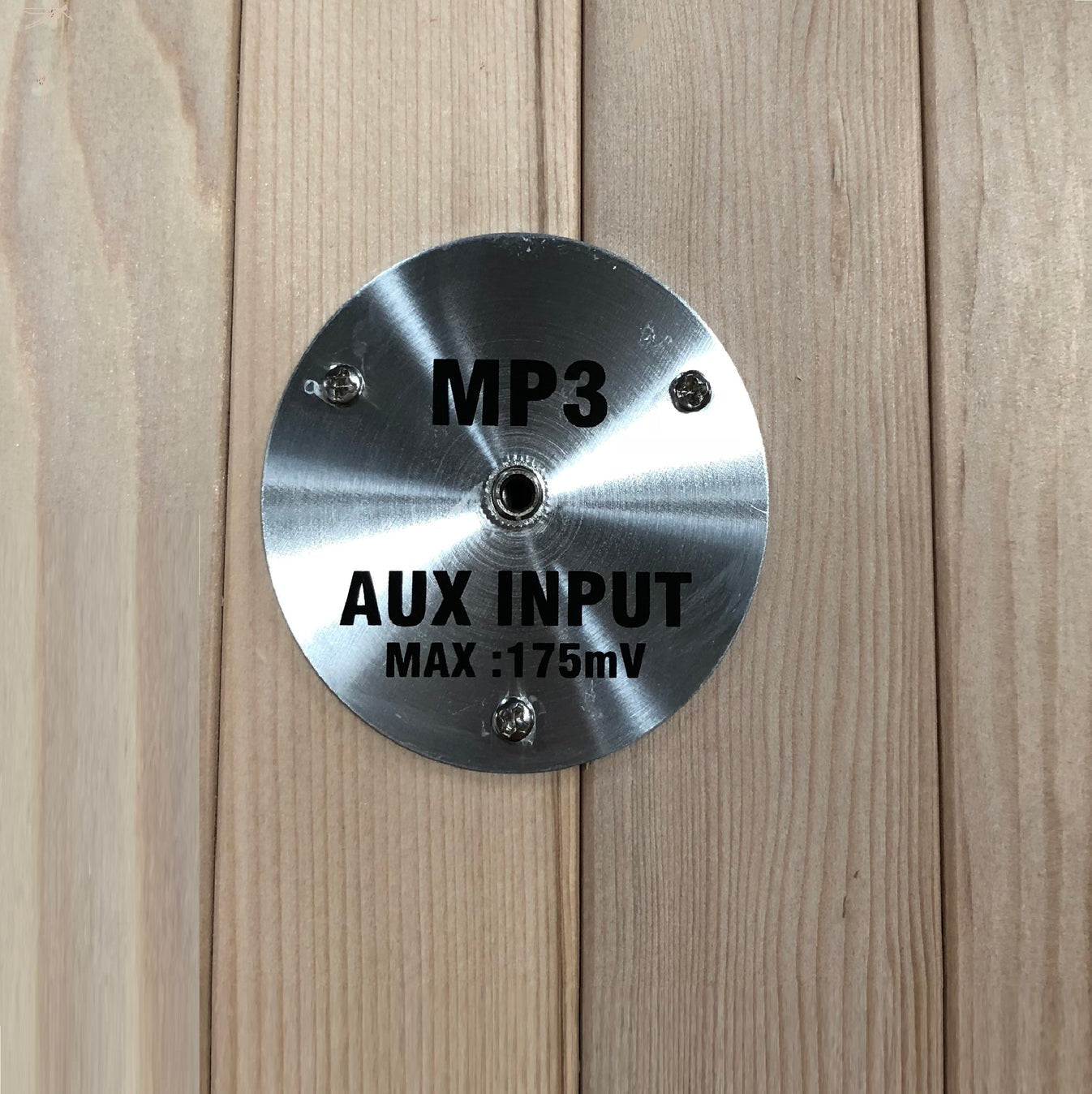Metallic label with 'MP3', 'AUX INPUT', and 'MAX: 175mV' text on a wooden surface